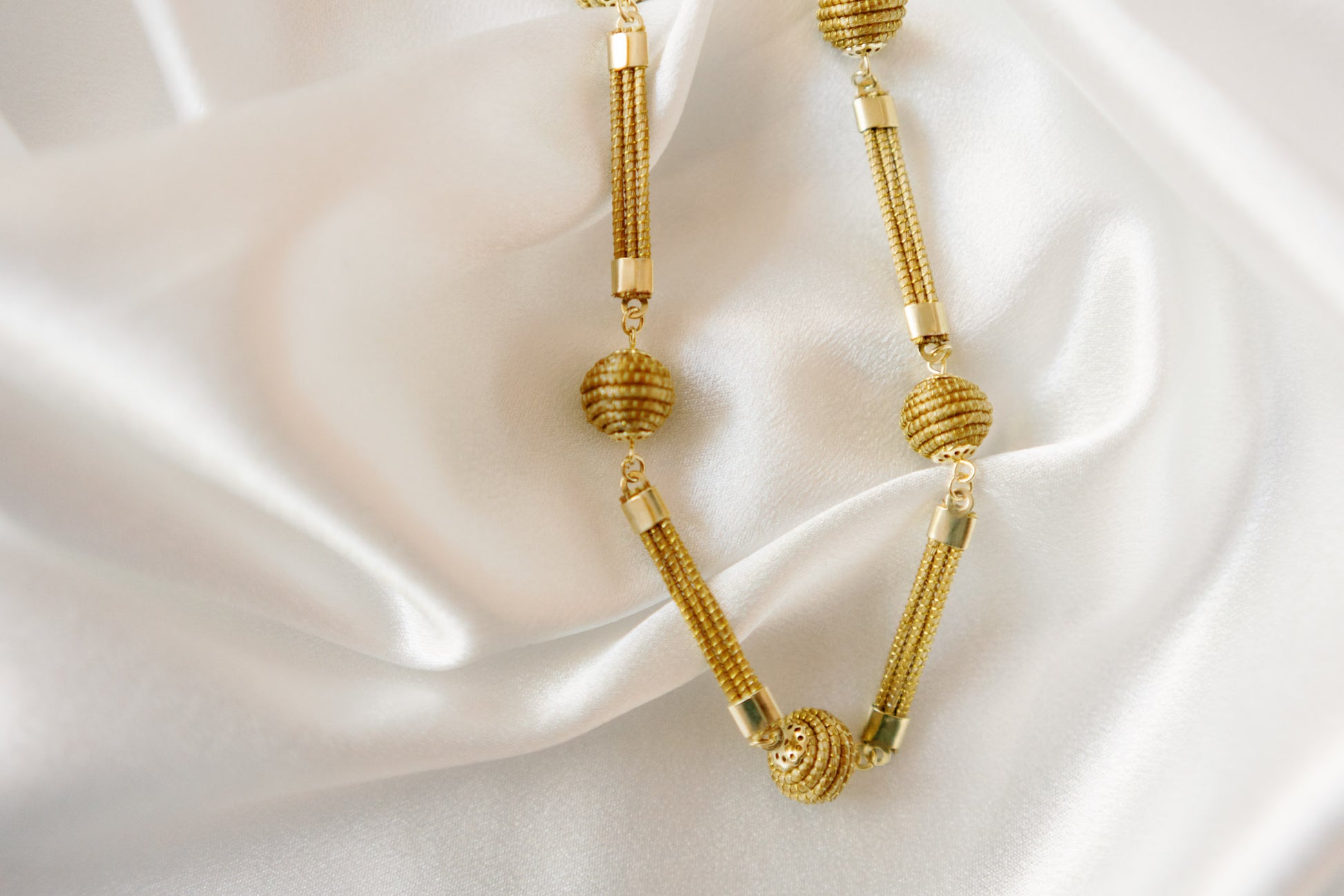 close up of golden grass beads and flat connectors on black suede cord sol necklace AquaBrasil jewelry
