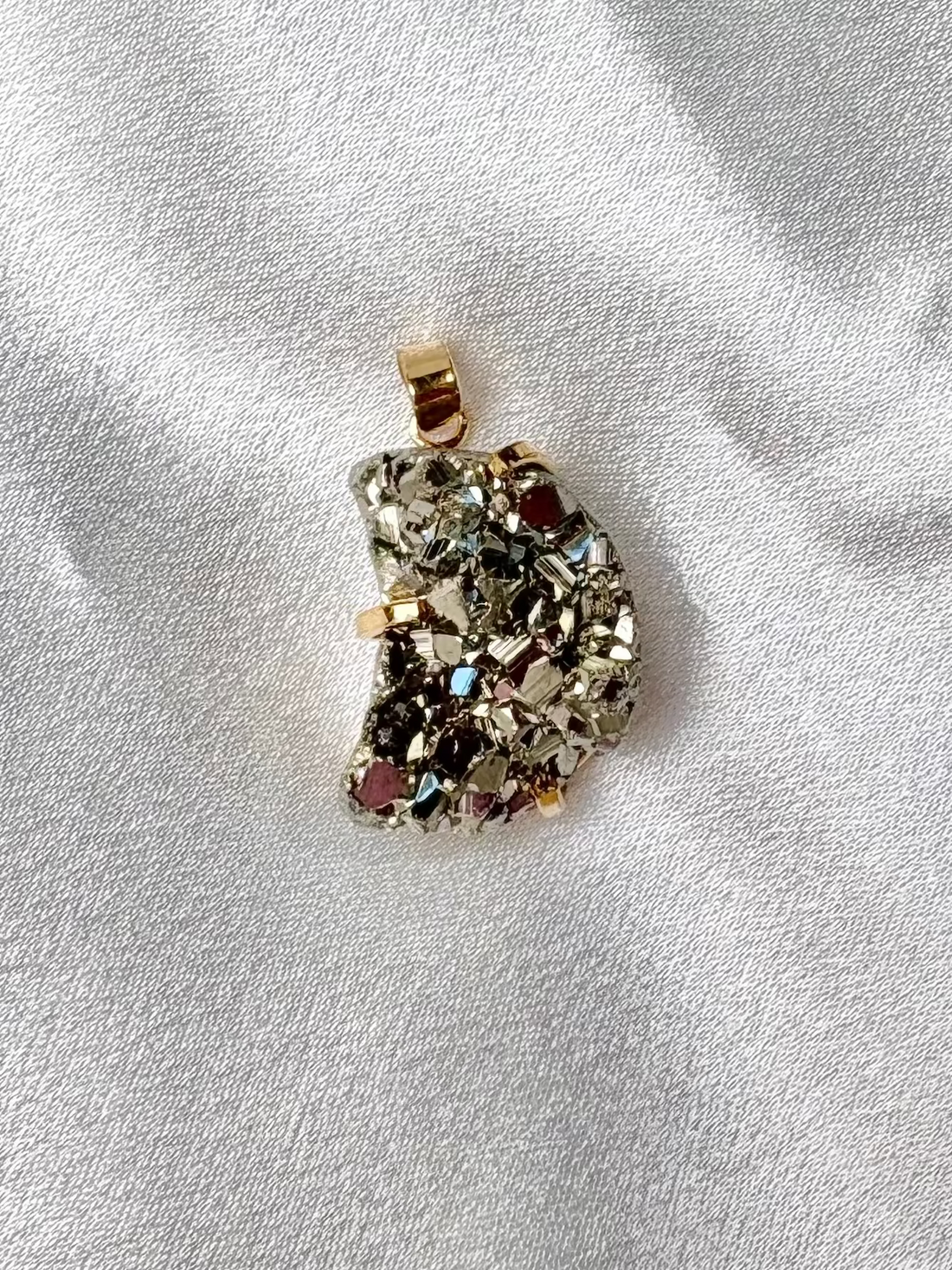 two large pyrite pendants handcrafted in Brazil one round and one moon shaped with 18k gold plated details AquaBrasil jewelry